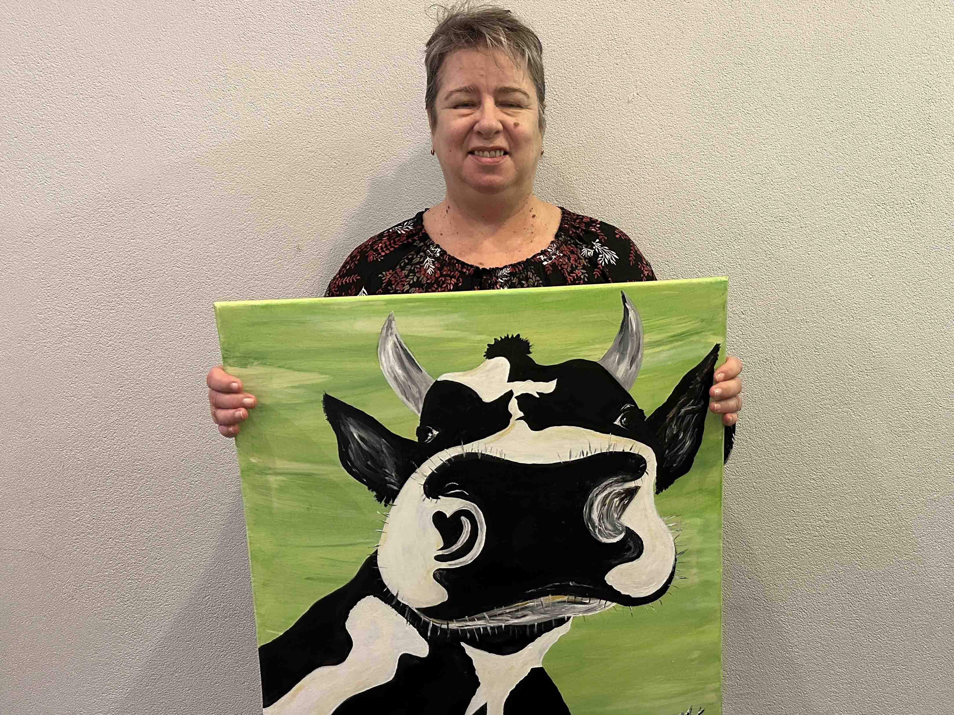 Foto Künstlerin Andrea Knebel mit einem selbstgemalten Bild einer Kuh 