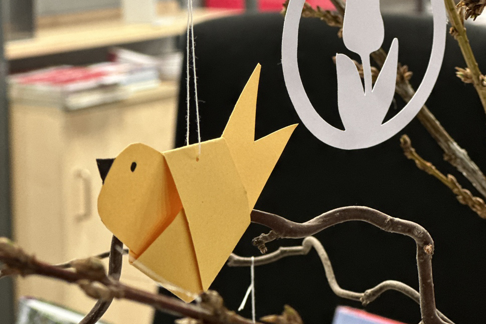 Foto gebastelter Papiervogel hängt im Frühlingsstrauß